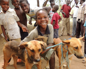 Kids in Africa pose with their vaccinated dogs.